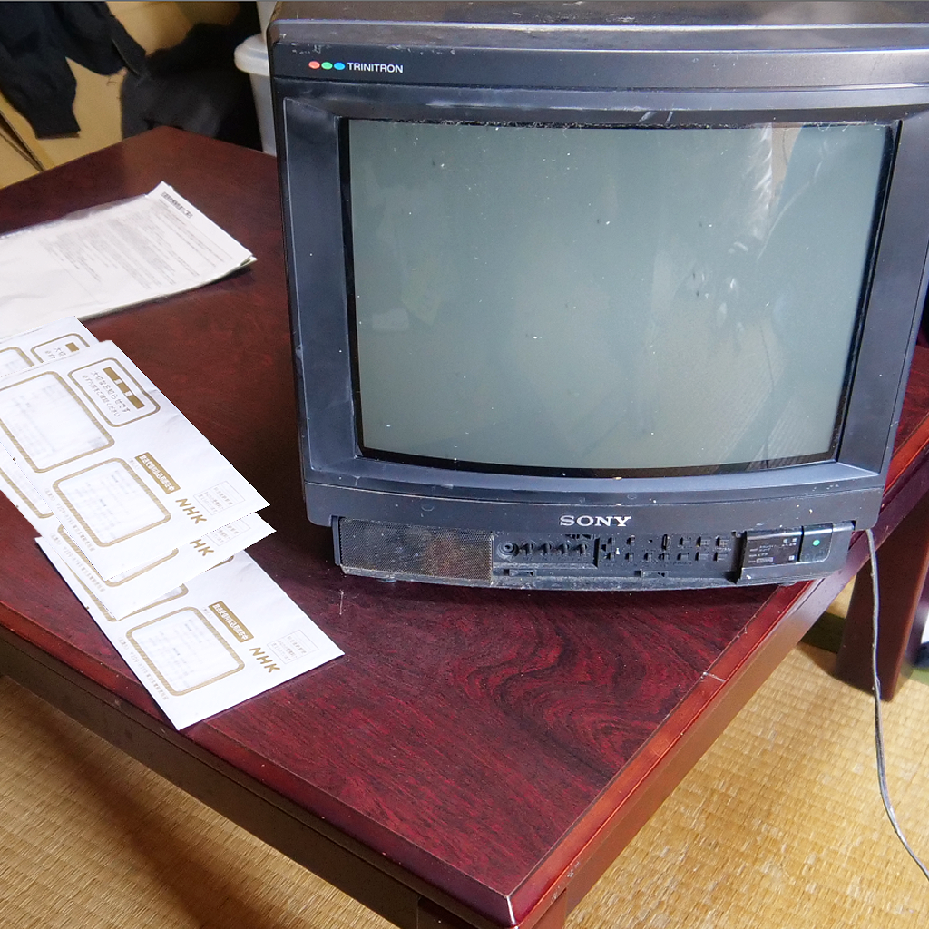 放置された古いテレビと分厚いNHK的請求書